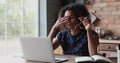 Tired African woman takes off glasses, resting from laptop work