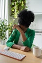 Exhausted African American woman having headache sits at office desk with keyboard. Burnout. Royalty Free Stock Photo