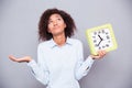 Tired afro american woman holding clock