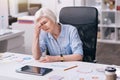 Tired aged businesswoman suffering from headache in the office