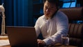 Tired angry Asian business man talking mobile phone at night evening office check documents working laptop overworked Royalty Free Stock Photo