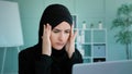 Tired Arabian Muslim Islamic woman in black hijab female worker student take short pause in online work feeling headache