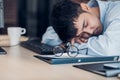 Tired asian businessman sleep on working desk table in office.working hard and late.burn out syndrome Royalty Free Stock Photo