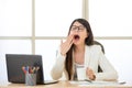 Tired Asian businesswomen yawing at desk
