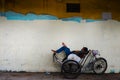 Tired Asian cyclo driver taking a nap on his cyclo with copy space for text or advertising on colorful background