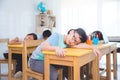 Tired asian elementary school student falling asleep while study