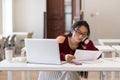 Tired bored asian female student reading printed paper materials while studying in library Royalty Free Stock Photo