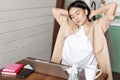 Tired asian girl having break from working, stretching arms after doing homework on laptop, sitting at home, works or Royalty Free Stock Photo