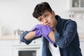 Tired asian guy leaning on broom, looking at copy space Royalty Free Stock Photo