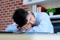 Tired asian man sleeping at office desk. Young businessman with eyeglasses overworked and fell asleep, Creative casual man