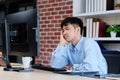 Tired asian man sleeping at office desk. Young businessman with eyeglasses overworked and fell asleep, Creative casual man