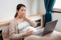 Tired asian pregnant woman yawning and using laptop on bed for working at her bedroom, remote working, Online shopping, Women Royalty Free Stock Photo