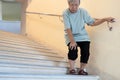 Tired asian senior woman going down the stairs with leg pain,touch her knee pain,female elderly with acute knee joint pain,