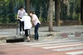 Tired asian senior woman with walker trying to climb the sidewalk after cross the road on crosswalk,facing the difficulties,