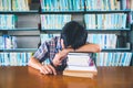 Tired asian student sleeping at the desk in a library Royalty Free Stock Photo