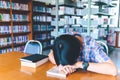 Tired asian student sleeping at the desk in a library Royalty Free Stock Photo