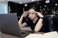 Tired asian student working at desk,use laptop computer for a long time on job,touching head with her hands,girl having a headache