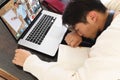 Tired asian teenage boy sleeping in front of laptop during online lecture on table at home Royalty Free Stock Photo