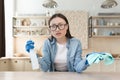 Tired Asian woman cleaning at home. Wipes the table with a rag in gloves and a bottle of spray Royalty Free Stock Photo