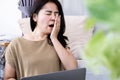 Tired Asian women feel sleepy and yawn while working on computer at home