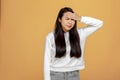 Tired asian young girl suffering from strong headache migraine, stressed dizzy woman feel head pain on yellow background