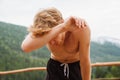 Tired athletic man resting after workout and wiping sweat from his forehead in mountains Royalty Free Stock Photo