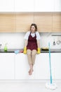 Tired attractive woman sits and on the kitchen furniture and feeling bad after exhausting cleaning day Royalty Free Stock Photo