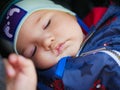 Tired baby sleeping in a stroller. Cute adorable caucasian blond toddler bou sleeping in stroller at daytime. Children healthcare Royalty Free Stock Photo