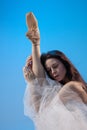 Tired ballet dancer sitting over blue studio background Royalty Free Stock Photo