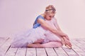 Tired ballet dancer sitting on the wooden floor Royalty Free Stock Photo