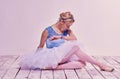 Tired ballet dancer sitting on the wooden floor Royalty Free Stock Photo