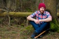 Tired bearded forester with an ax on the relax