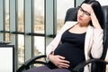 Tired beautiful pregnant woman sitting at workplace Royalty Free Stock Photo