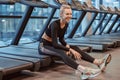 Tired beautiful young blond woman with sweat on body rest and drink water after break running on treadmills in sport