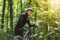 Tired biker having rest among green trees in sun flare