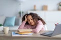 Tired black schoolgirl sleeping at desk doing homework at home. School overload concept