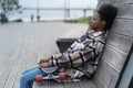 Tired afro skateboarder girl sitting alone on bench in urban open space depressed ponder outdoors Royalty Free Stock Photo