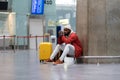 Tired Black tourist man on a long night connection at airport, waiting for plane sitting in terminal Royalty Free Stock Photo