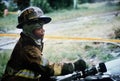 Tired Black volunteer firefighters pours water on burning house