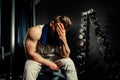 Tired bodybuilder athlete with protein shaker and towel in gym