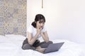 Tired and bored asian beautiful girl when work the laptop in the bed. Work from home concept Royalty Free Stock Photo