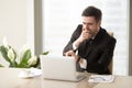 Tired bored businessman yawning at workplace, checking time on w Royalty Free Stock Photo