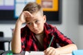 Tired, bored caucasian schoolboy sitting at desk, listening in class