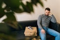 Tired bored delivery man waiting customer while sitting on sofa with boxes pizza, cardboard box and payment POS terminal Royalty Free Stock Photo