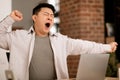 Tired bored middle aged asian man yawning while sitting at workplace with computer, wants to sleep at home interior Royalty Free Stock Photo