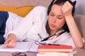 Tired and bored pretty brunette young woman studying stretched out on the sofa at home listening to music through headphones.