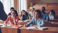 Tired and bored students are listening to teacher and making notes in notebooks sitting at desks in university Royalty Free Stock Photo