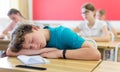 Tired bored teenage schoolboy sleeping at desk Royalty Free Stock Photo