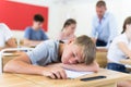 Tired bored teenage schoolboy sleeping at desk Royalty Free Stock Photo