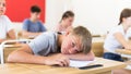 Tired bored teenage schoolboy sleeping at desk Royalty Free Stock Photo